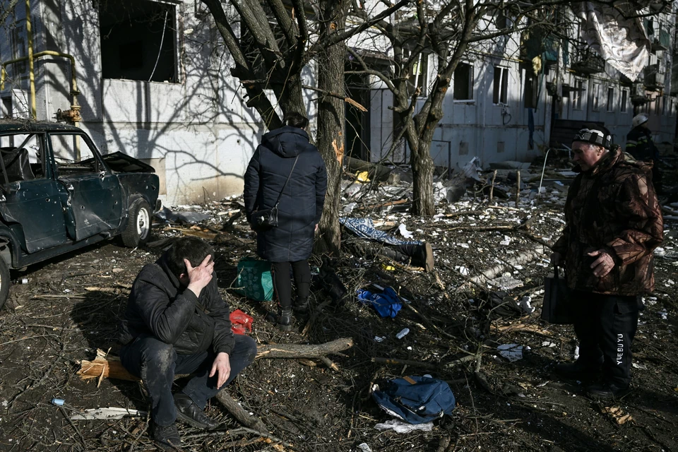 Mężczyzna siedzi przed zniszczonym budynkiem po bombardowaniach miasta Czuhujew na wschodzie Ukrainy